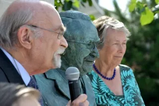 Dr Dennis Guttmann and Eva Loeffler beside the bronze statue of their father